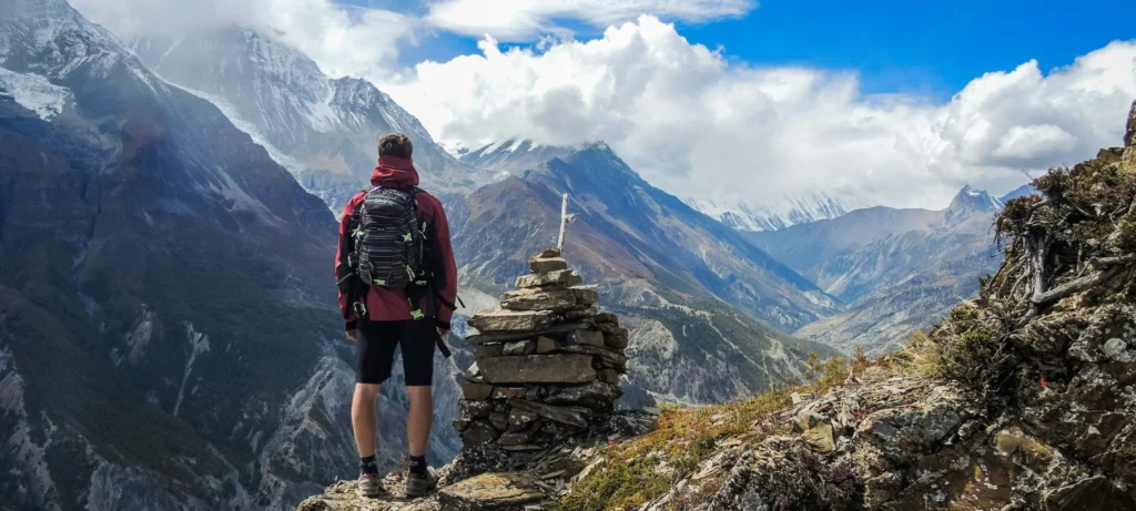 Bhakra, Nepal - A trekker with a backpack stands on a rocky mountain ridge in Nepal
