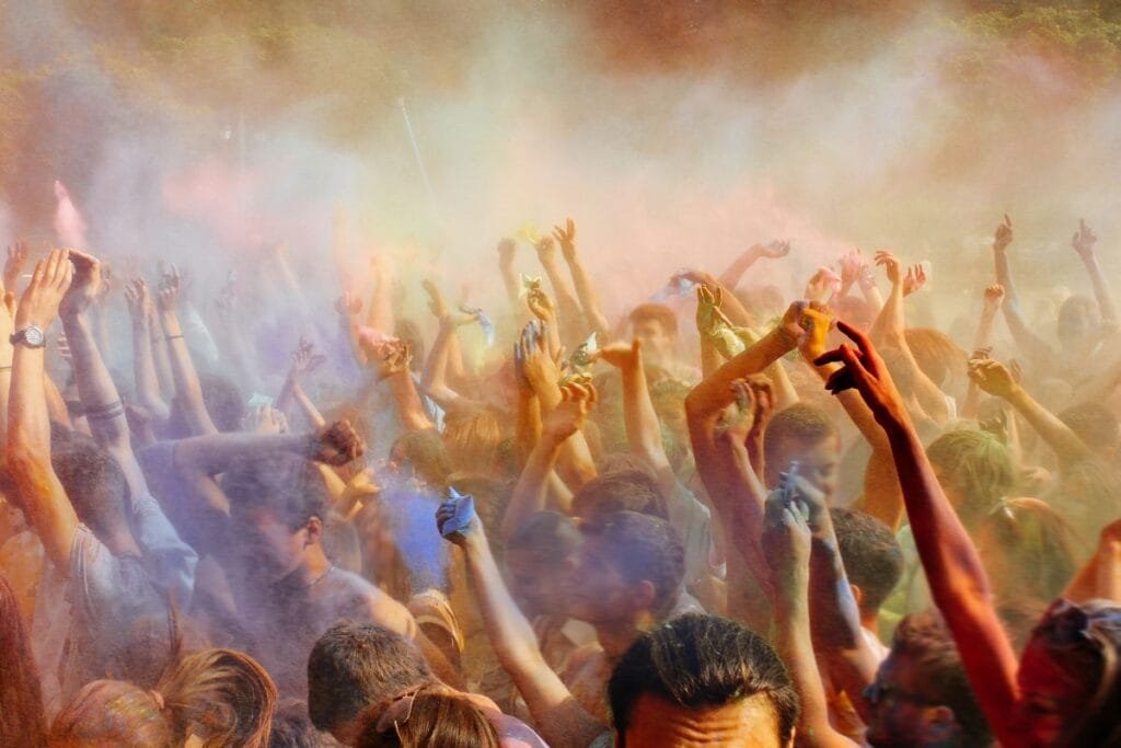 Happy People Crowd Partying under Colorful Powder Cloud at Holi