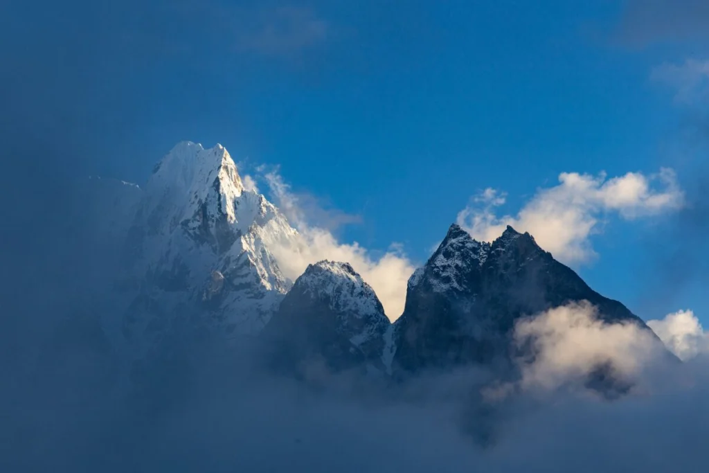 Ama Dablam peak rising above clouds in the Everest region of Nepal under a clear blue sky.